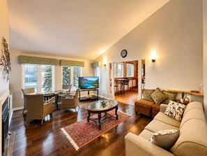 A living room with a television, wicker furniture, a glass coffee table, a red rug, and a sofa. - Canalside summer cottage w/ river views, fire table & outdoor cushioned seating (Brechin)