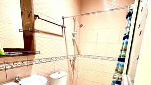 A bathroom with a sink, toilet, shower, and a mirror.