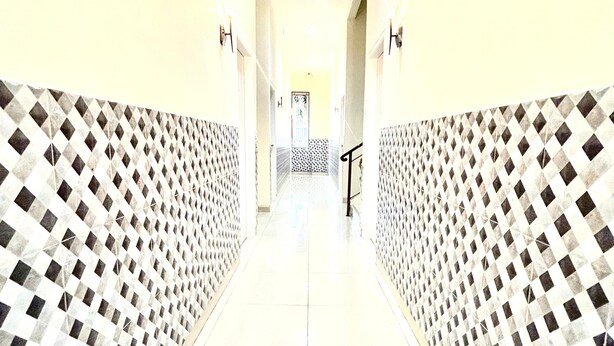 A corridor with patterned walls and a tiled floor, leading to a door at the end.