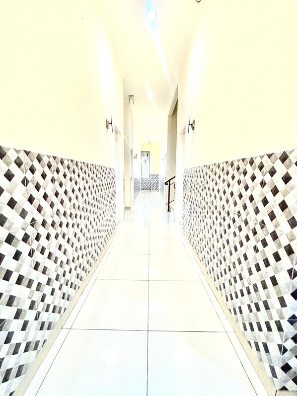 A corridor with patterned walls and a tiled floor, leading to a door at the end.