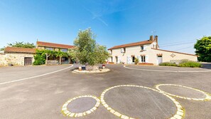 A building with a tiled roof, a central circular driveway, and a small tree in the middle. - Two gîtes in the countryside for 25 people: indoor swimming pool and play areas (Montrevault-sur-Èvre)