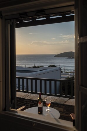 Ein Balkon mit Meerblick, eine Weinflasche und ein Glas auf einem Tisch.
