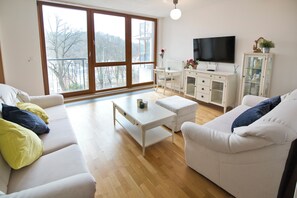 Ein Wohnzimmer mit einem weißen Sofa, einem weißen Couchtisch, einem Fernseher und einer Vitrine.