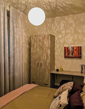 Ein Schlafzimmer mit einem Bett, einem Kleiderschrank, einem Schreibtisch und einer Wandlampe.