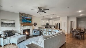 Una sala de estar moderna con chimenea, un sofá, un televisor y un comedor con sillas de madera y una mesa.
