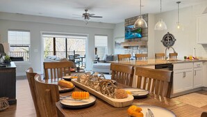 Un comedor con una mesa de madera dispuesta para una comida, una cocina con armarios blancos y una chimenea de piedra.