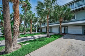 A multi-story building with a parking garage, surrounded by palm trees and a well-maintained lawn.