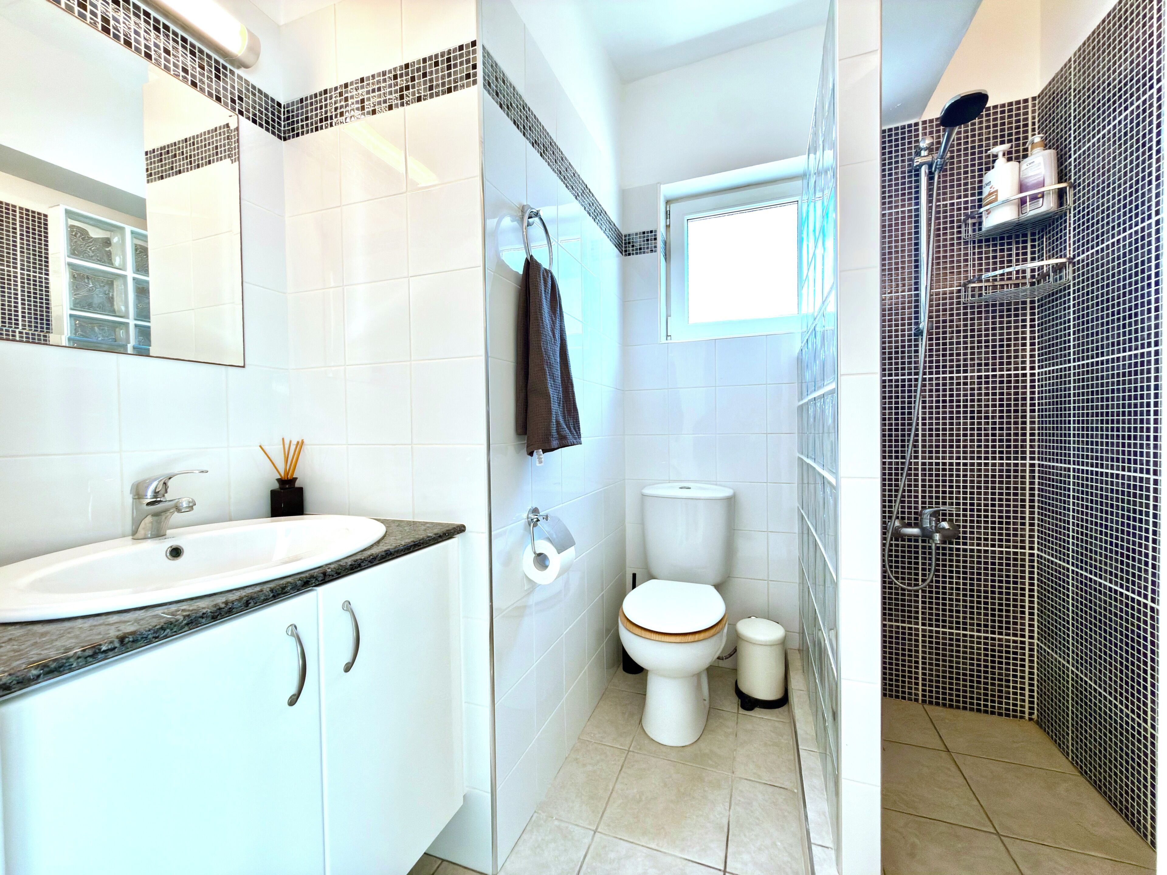 A bathroom with a white sink, toilet, and shower area.
