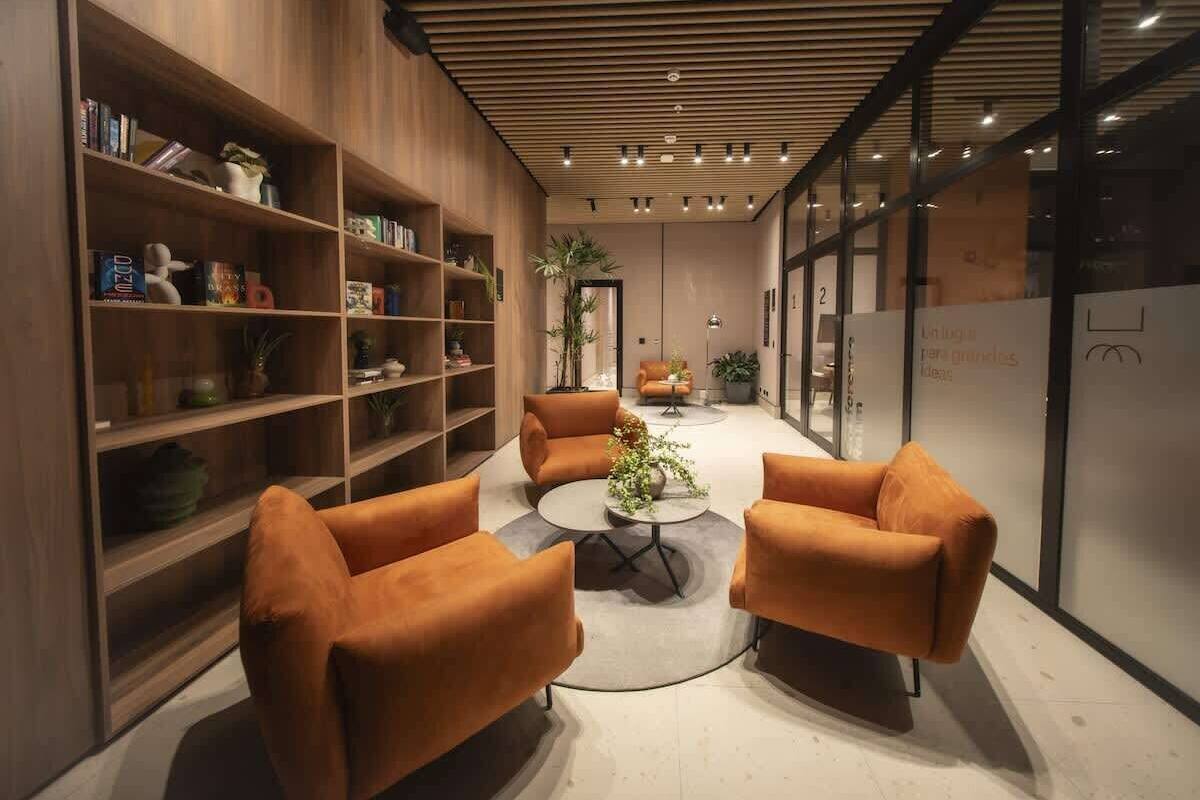 Un interior moderno con estanterías de madera, sofás naranja y una mesa de centro.