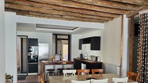 Eine moderne Küche mit Einbauofen, einem Essbereich mit Tisch und Stühlen sowie einer Holzausstattung an der Decke.