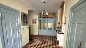 A hallway with checkered flooring, blue doors, and a chandelier. - Engelapartment in the Villa Schulenburg (Putbus)