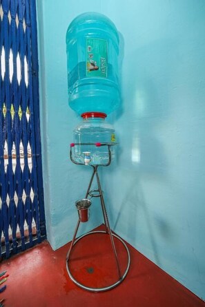 Um bebedouro fixado na parede, com uma porta azul ao fundo.