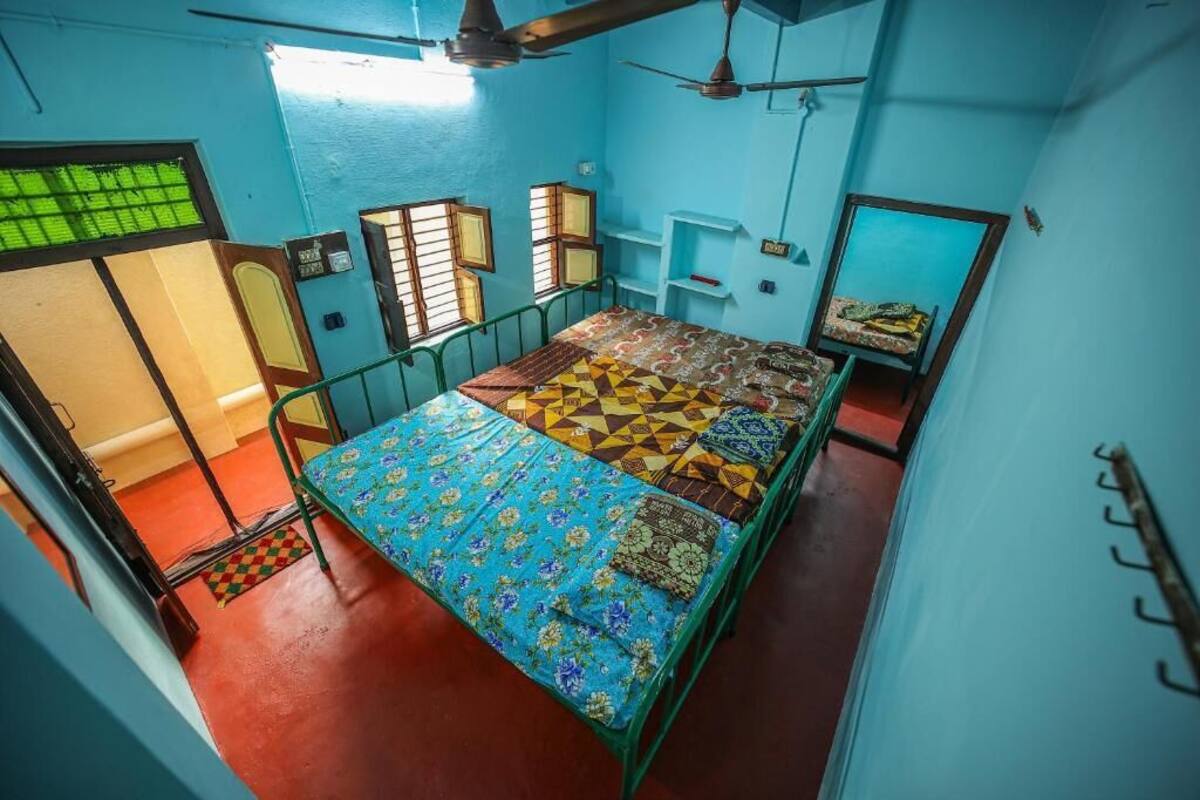 A room with a bed, a window, a door, and a ceiling fan.