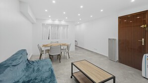 A room with a bed, a small table, a dining table with chairs, a wooden door, and a white wall. - 🏡 Charming renovated 2-room apartment - Ideal location behind the Martinez in Cannes (Cannes)