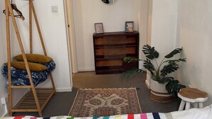 A bedroom with a bunk bed, a bedside table with a mirror, a small plant, and a colorful striped blanket.