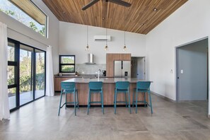 Eine moderne Küche mit einer zentralen Kochinsel, Barhocker und einem Deckenventilator.