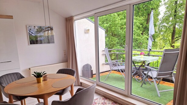 A room with a large window, a round table with chairs, a radiator, and a potted plant. - Fantastic vacation apartment "Haus am Meer" in Bad Zwischenahn with top location by the sea (Bad Zwischenahn)