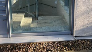 A modern building with a glass entrance, metal railings, and a staircase leading to an upper level. - Fantastic vacation apartment "Haus am Meer" in Bad Zwischenahn with top location by the sea (Bad Zwischenahn)