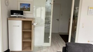A room with a desk, a chair, a sliding glass door, and a clock on the wall. - Fantastic vacation apartment "Haus am Meer" in Bad Zwischenahn with top location by the sea (Bad Zwischenahn)