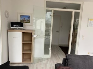 Une pièce comprenant un bureau, une chaise, une porte-fenêtre coulissante et une horloge au mur.