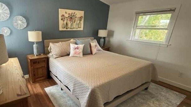 Une chambre à coucher comprenant un lit, des tables de chevet, un ventilateur de plafond, une fenêtre et des éléments de décoration murale.
