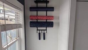 Un coin de pièce avec un banc, une étagère fixée au mur ornée d’objets décoratifs et une fenêtre avec des stores.