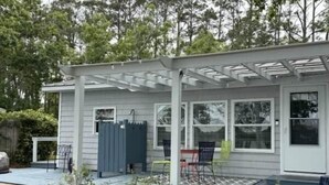 Une maison de plain-pied avec un porche couvert, une petite terrasse et une cour clôturée.