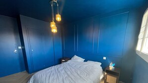 Une chambre à coucher avec un lit, des tables de chevet, une armoire et une fenêtre.