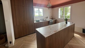 Une cuisine moderne avec des meubles en bois, un plan de travail en marbre et une fenêtre qui laisse entrer la lumière naturelle.
