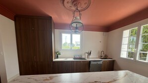 Une cuisine dotée d’un plan de travail en marbre, de meubles en bois, d’une fenêtre et d’un luminaire au plafond.