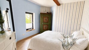 Une chambre à coucher avec un lit, une fenêtre, une commode et une porte verte.