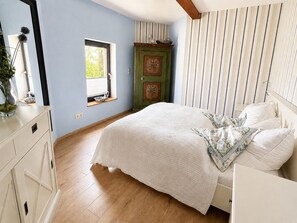 A bedroom with a bed, a window, a dresser, and a green door. - Putbus water tower - exceptional accommodation on Rügen (Putbus)