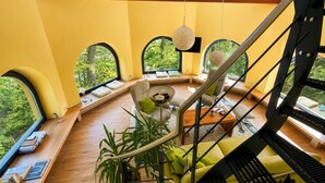 Un intérieur moderne avec un escalier à volutes, de grandes fenêtres et une vue sur la verdure environnante.