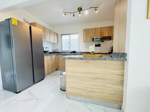 Eine moderne Küche mit Edelstahlgeräten, Holzschränken und einer Arbeitsplatte aus Granit.