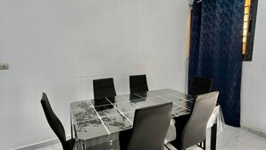 A dining area with a marble-tiled floor, a glass-top table, and six chairs.