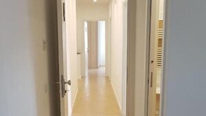 Un pasillo con un sofá, una puerta y una rejilla de ventilación en el techo.