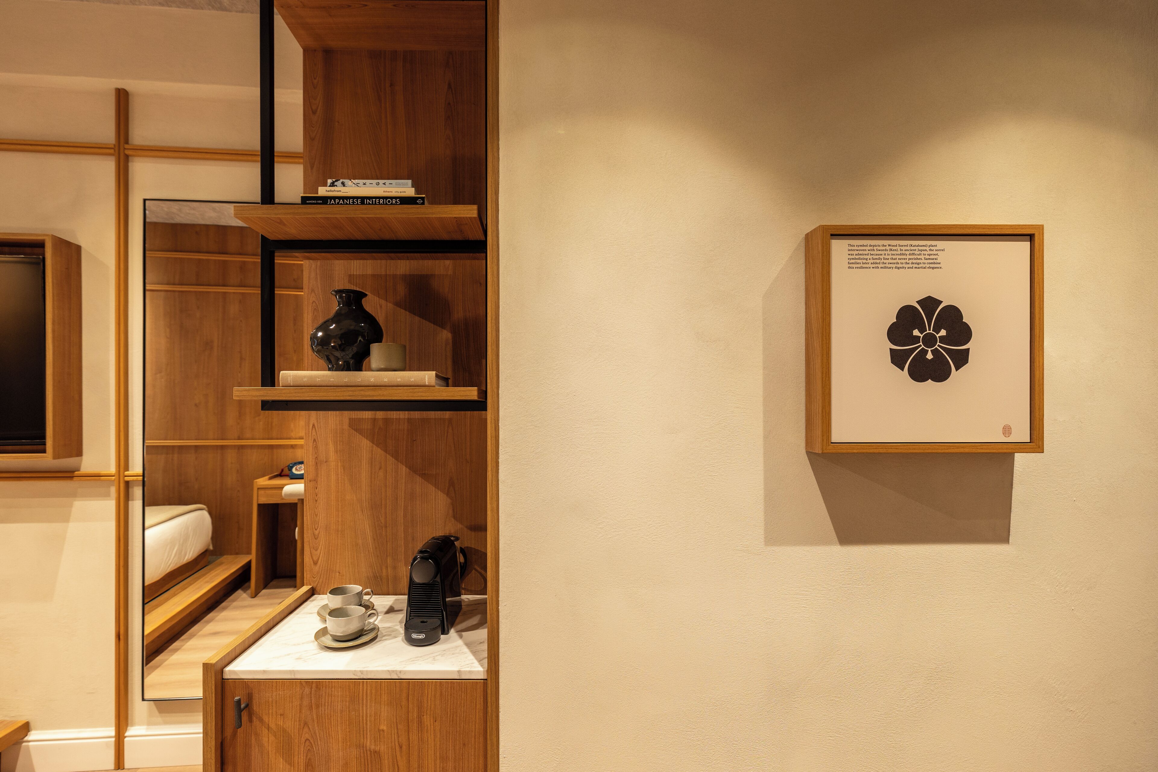 A hotel room with a wooden cabinet, a small table with a cup and a remote control, and a framed picture on the wall.
