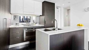 Et moderne køkken med en central ø, stålstål-hvidevarer og et minimalistisk design.