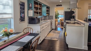 A modern kitchen with white cabinetry, a central island, and a chalkboard sign.