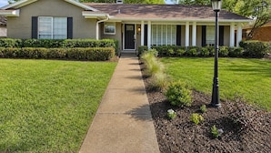 A residential house with a front porch, a pathway leading to the entrance, and a well-maintained lawn.