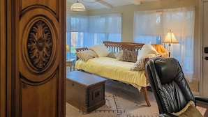 A bedroom with a bed, a chair, a desk, and a lamp.