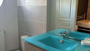 Ein Badezimmer mit Toilette, einem Waschbecken aus Glas und einem Spiegel.