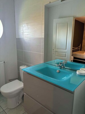 Ein Badezimmer mit Toilette, einem Waschbecken aus Glas und einem Spiegel.