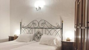 Ein Schlafzimmer mit Bett, Nachttischen, einem Kleiderschrank und einer Decke mit Holzbalken.