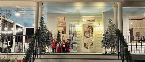 Un edificio de dos pisos con una entrada imponente, una escalera adornada con lazos rojos y decoraciones navideñas.
