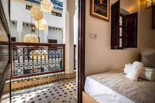 A room with a bed, a balcony with decorative lights, and a view of the outside.
