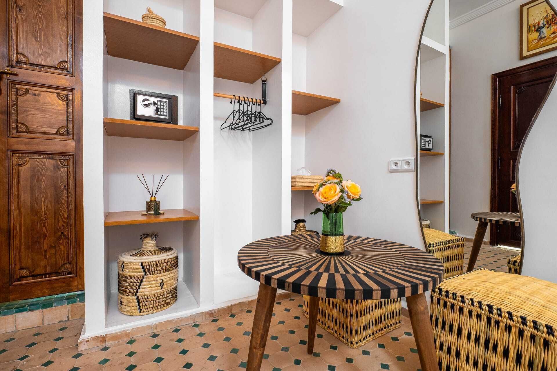 A room with a round table, shelves, a mirror, and a patterned floor.