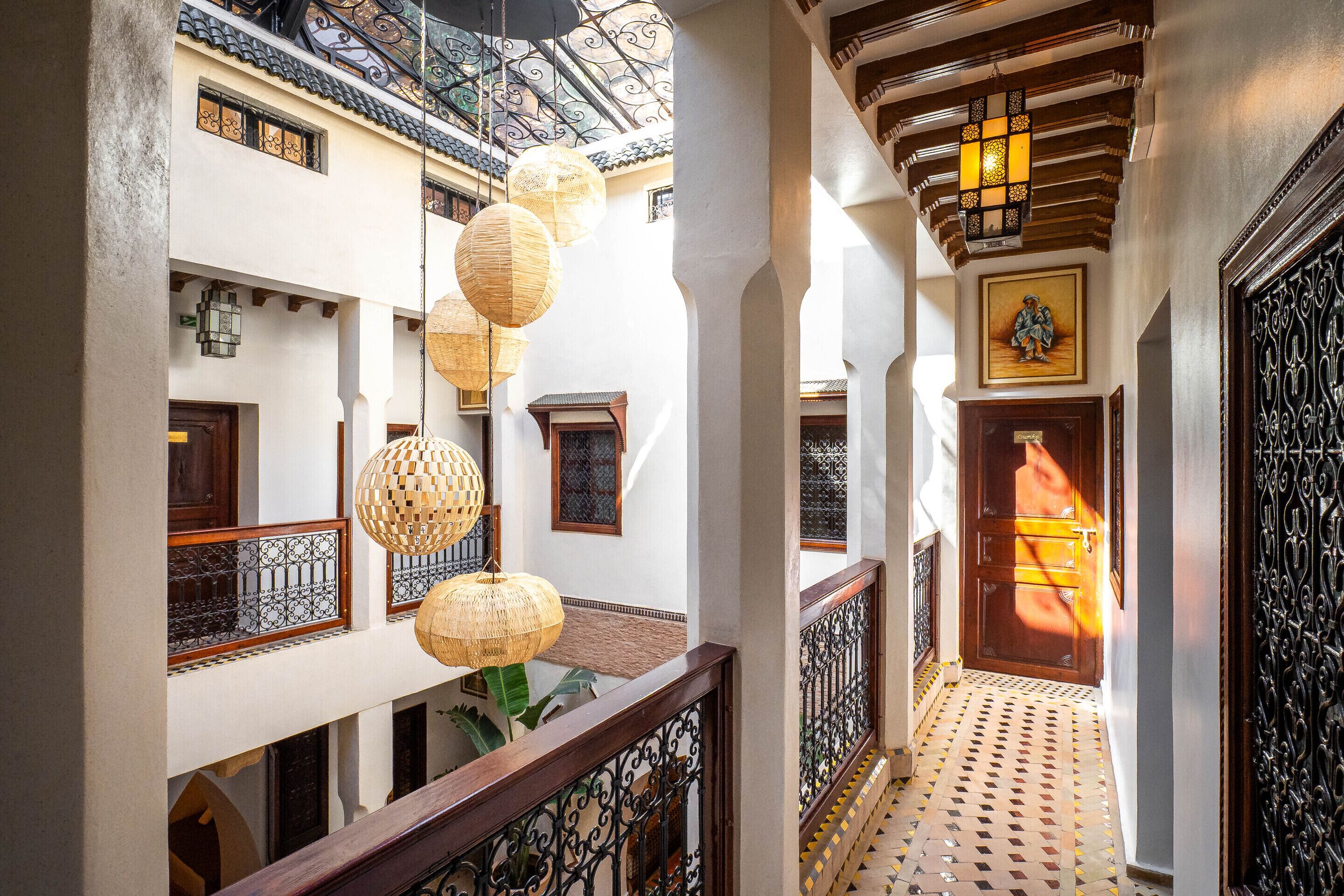 A multi-level interior with traditional design elements, including a balcony, ornate railings, and hanging paper lanterns.