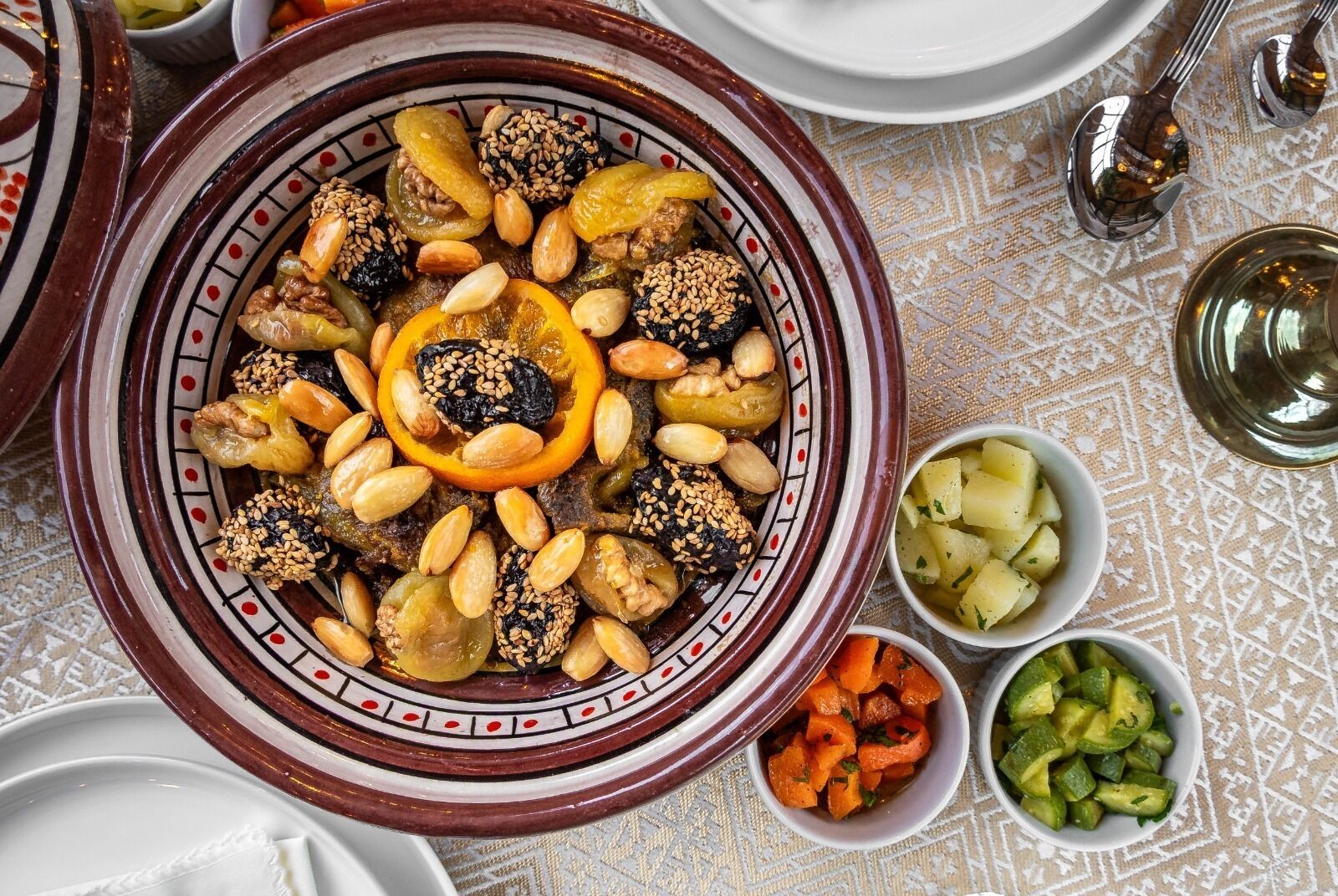 A traditional Moroccan tagine dish with nuts and dried fruits, accompanied by small bowls of vegetables.
