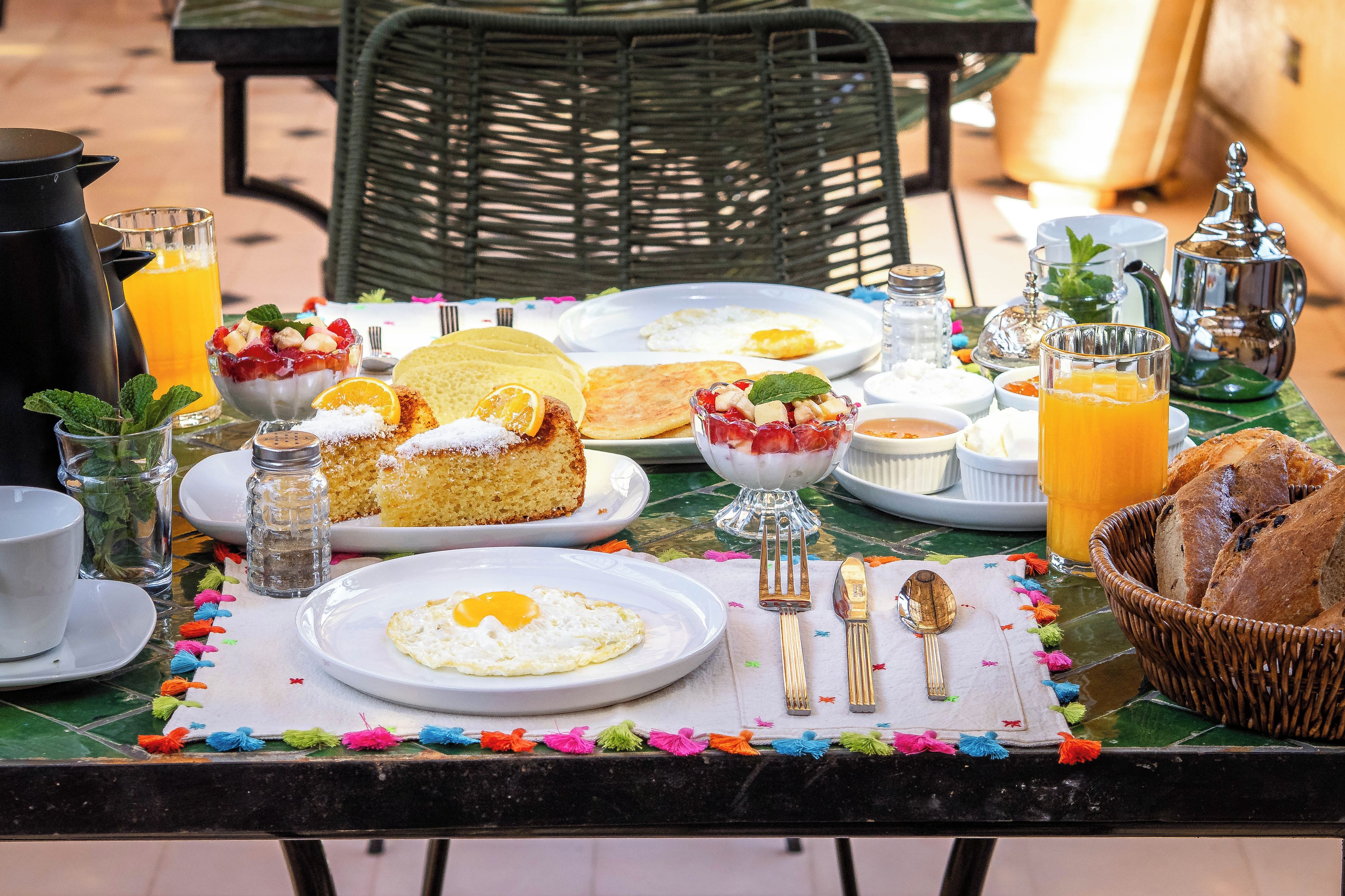 A breakfast table set with plates, a teapot, a pitcher, and a glass of orange juice.